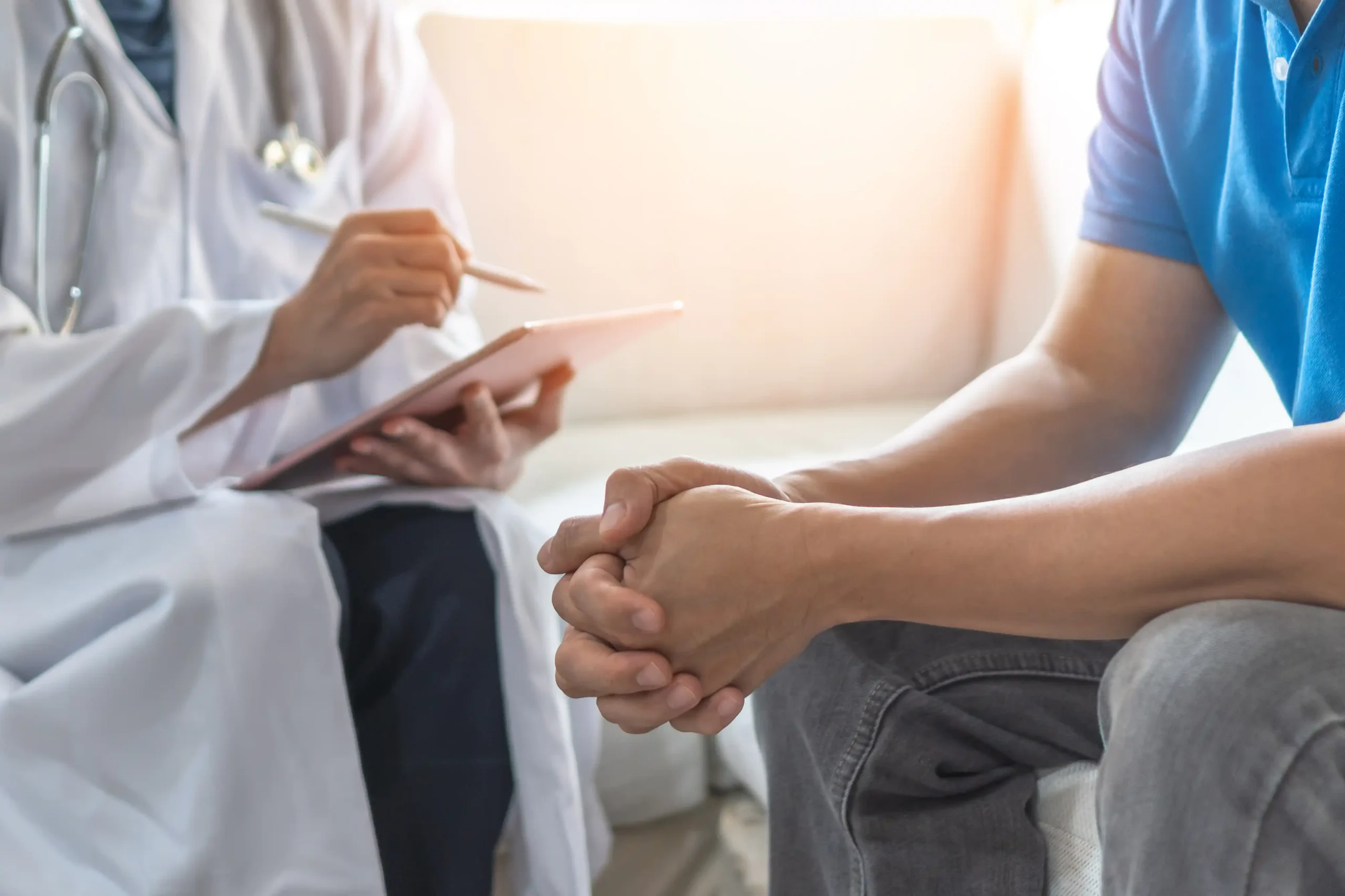 A physician taking notes on a tablet while talking with a patient